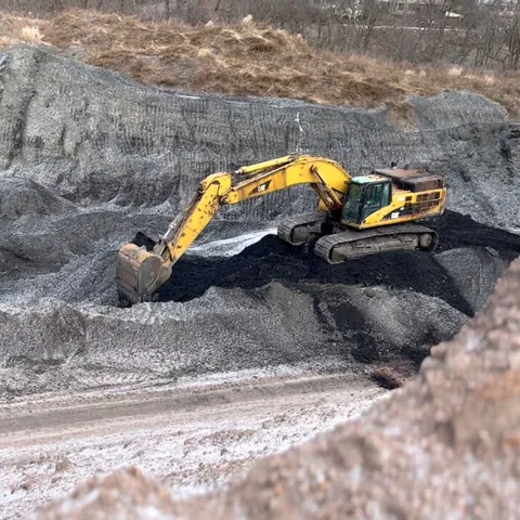 A yellow excavator working in a stepped excavation